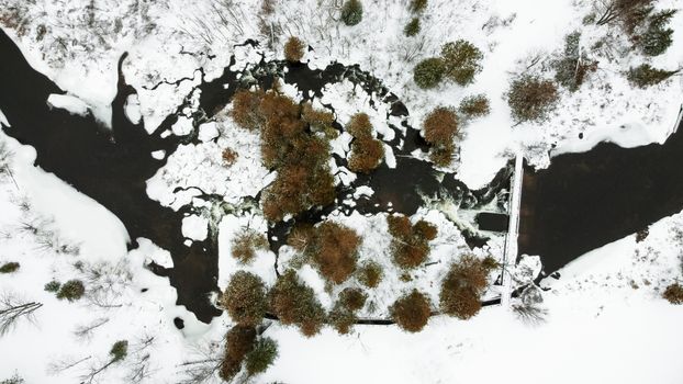 A breathtaking aerial shot of a snow-covered river and surrounding landscape, showcasing winter's natural beauty.