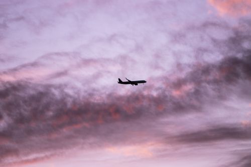 Free An airplane flies against a dynamic twilight sky with pink and purple hues in Porto, Portugal. Stock Photo