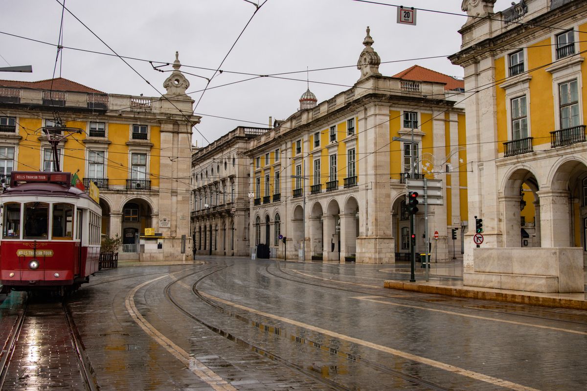 Traditional tram in Lisbon's iconic Praça do Comércio on a rainy day, showcasing classic architecture.