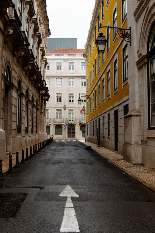Free Empty street in Lisbon showcasing traditional Portuguese architecture and vibrant yellow facade. Stock Photo