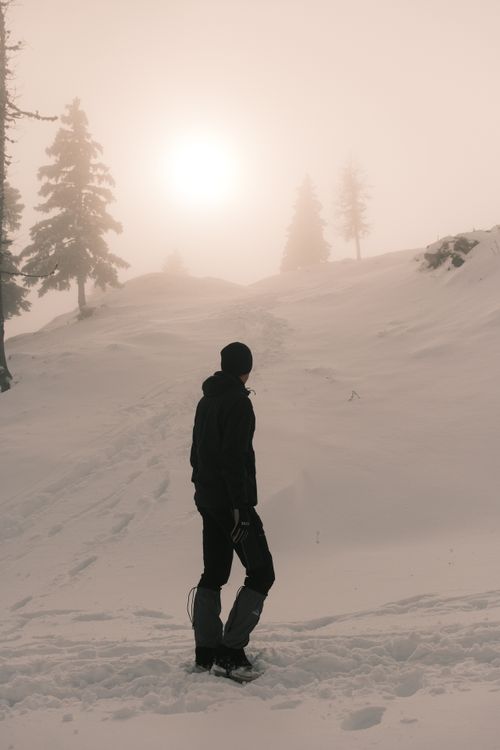 Free Silhouette of a person hiking in a snowy mountain landscape at sunrise. Stock Photo