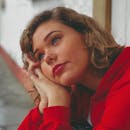 一位表情柔和、穿着红色夹克的女人在户外憧憬着梦想