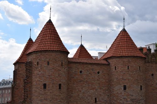 Free Majestic medieval brick towers of Warsaw Barbican against a partly cloudy sky. Stock Photo