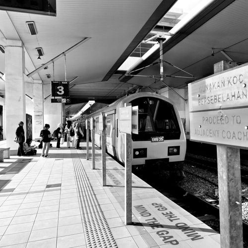 Free Black and white image of a train station platform in Butterworth, Malaysia with passengers. Stock Photo