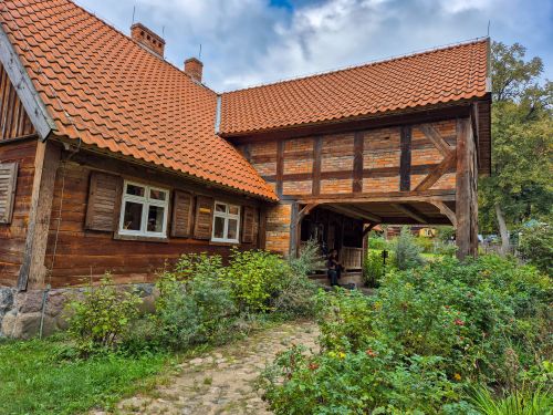 Free Charming rustic wooden house featuring a red tile roof and lush garden outdoor view. Stock Photo