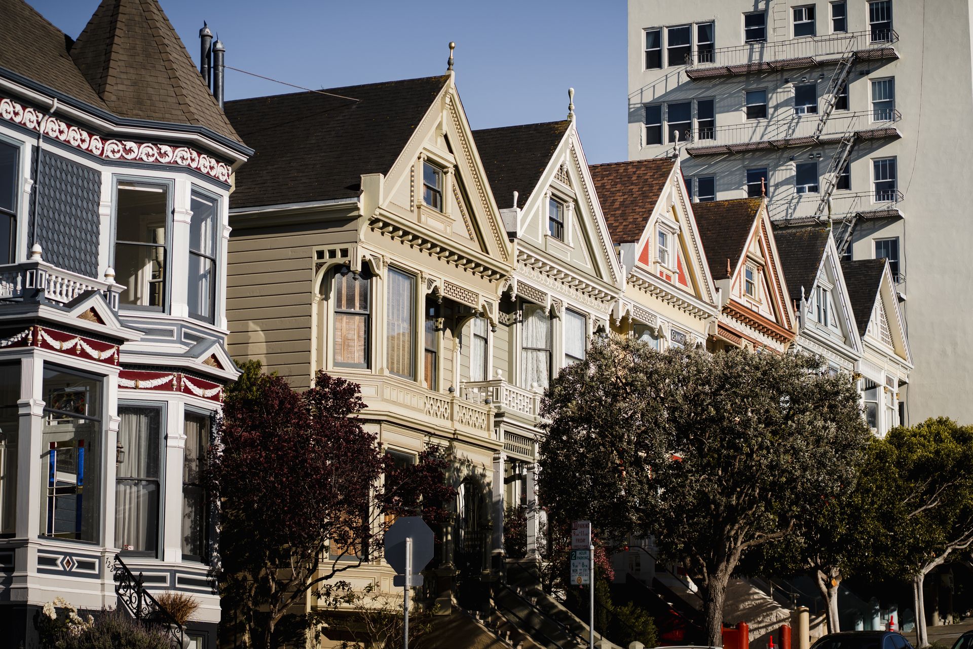Row of colorful Victorian houses with ornate gables on a sunny San Francisco street