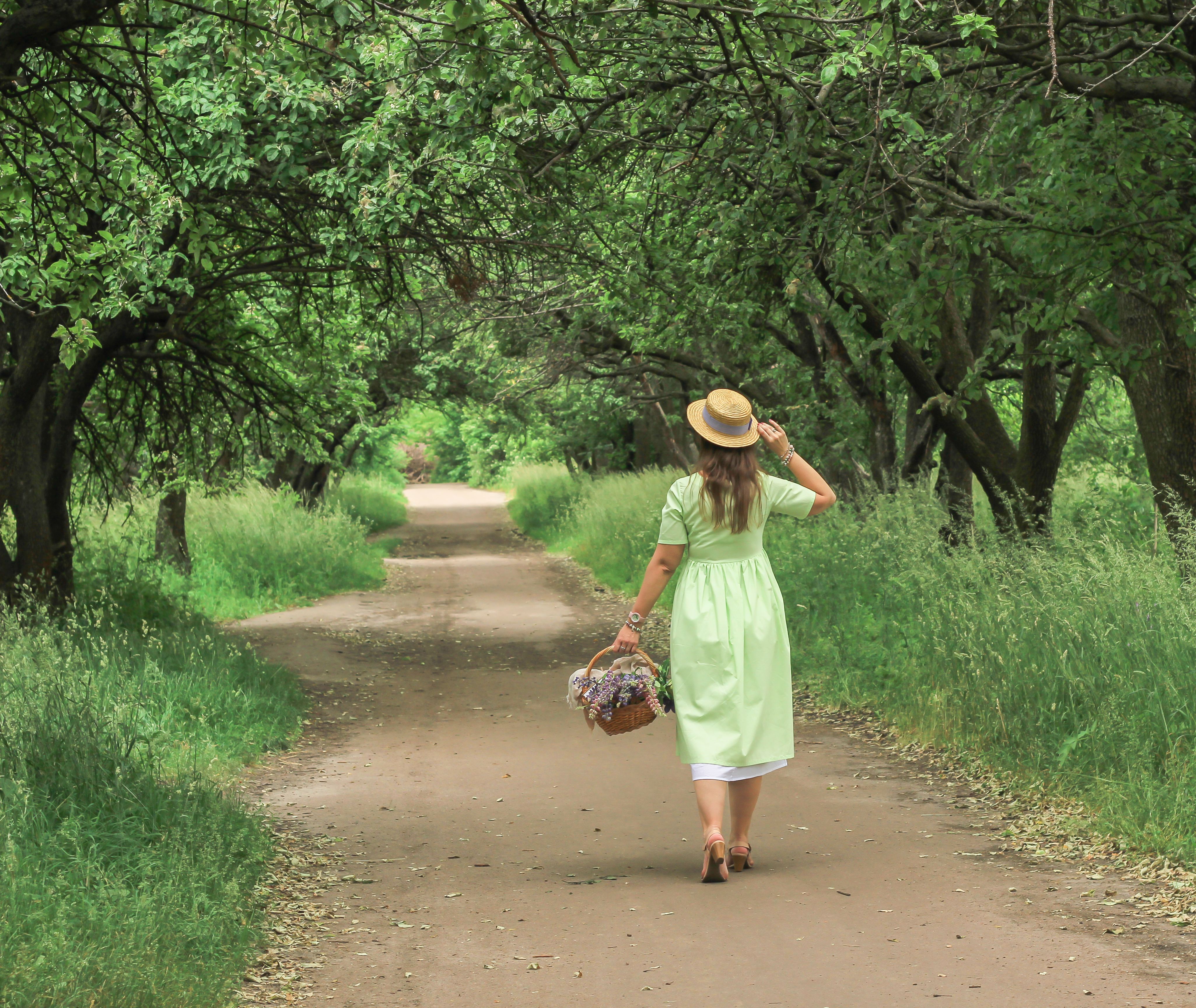 Woman Walking Through a Lush Green Pathway in Summer · Free Stock Photo