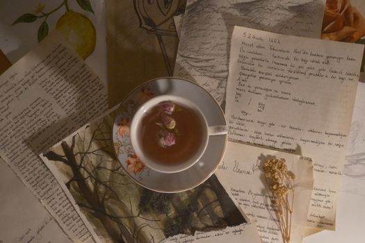 Aesthetic vintage still life featuring a cup of floral tea surrounded by handwritten letters and drawings.