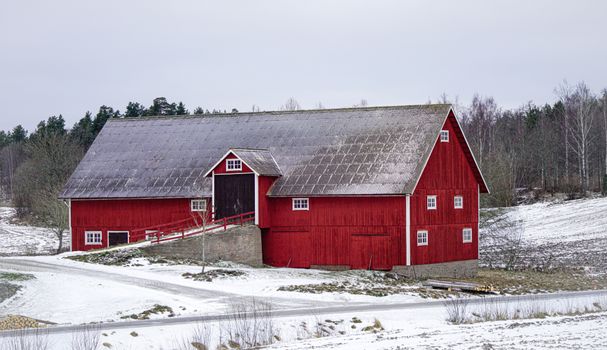 Quaint red barn in a snowy winter landscape, Jonkoping County, Sweden.