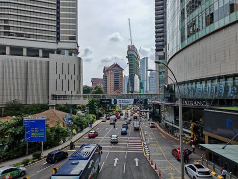 Bustling city street with vehicles amidst skyscrapers in Kuala Lumpur, Malaysia.