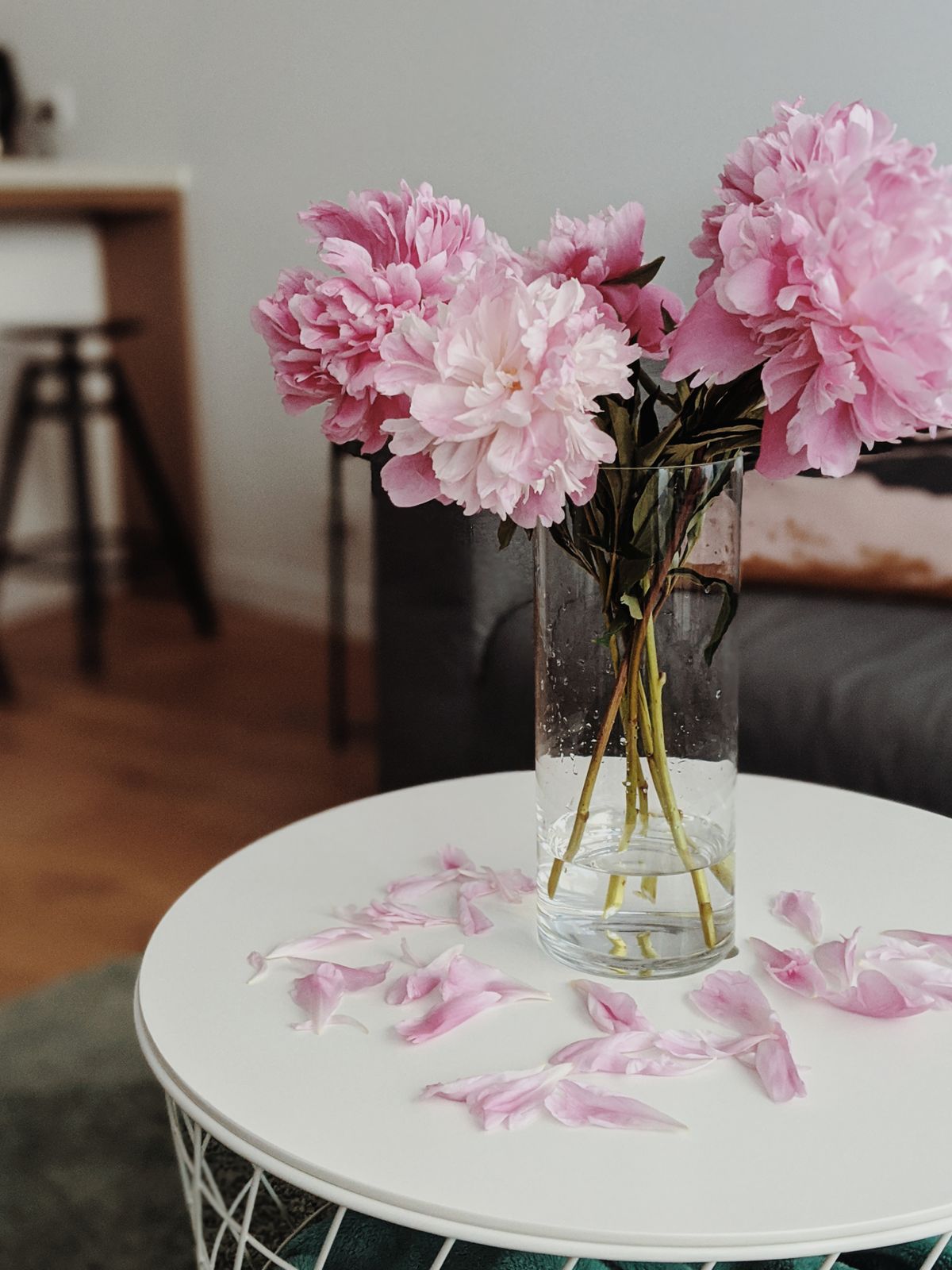 Cut pink peonies arranged in a glass vase on a modern table