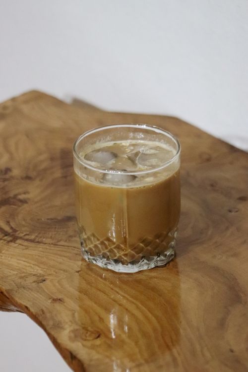 Free A glass of iced coffee with ice cubes on a rustic wooden table, perfect for a refreshing break. Stock Photo