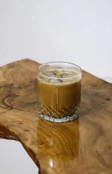 A refreshing iced coffee in a clear glass placed on a rustic wooden table, perfect for a coffee break.