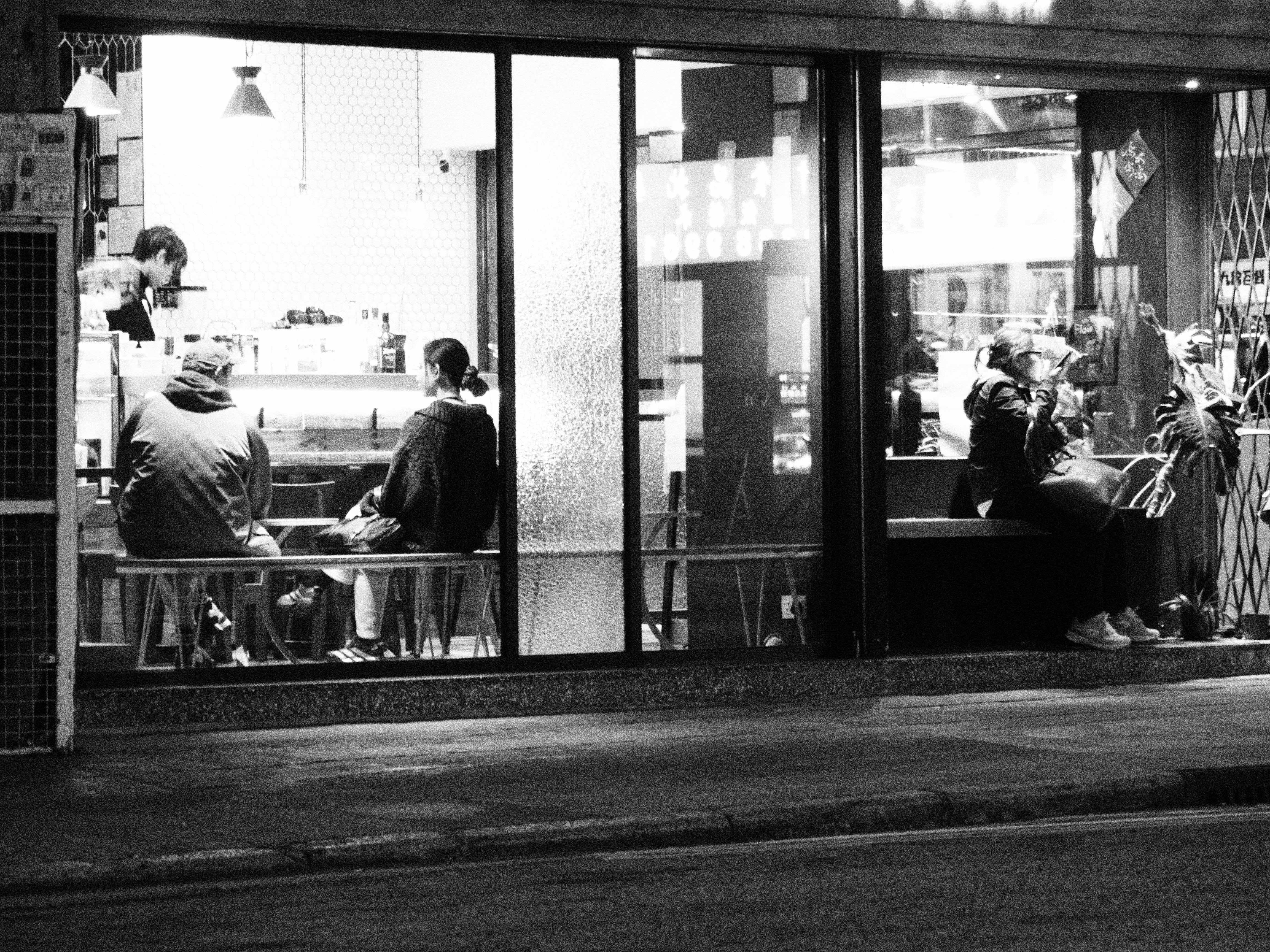 Street view of people enjoying a night in a Hong Kong cafe, highlighting urban life.