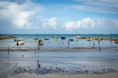 Free Serene coastal scene with boats moored on clear blue waters under a bright sky. Stock Photo