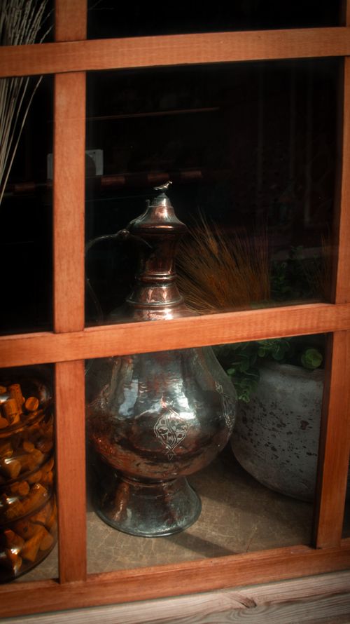 Free A vintage brass jug seen through a wooden window, offering a rustic feel. Stock Photo