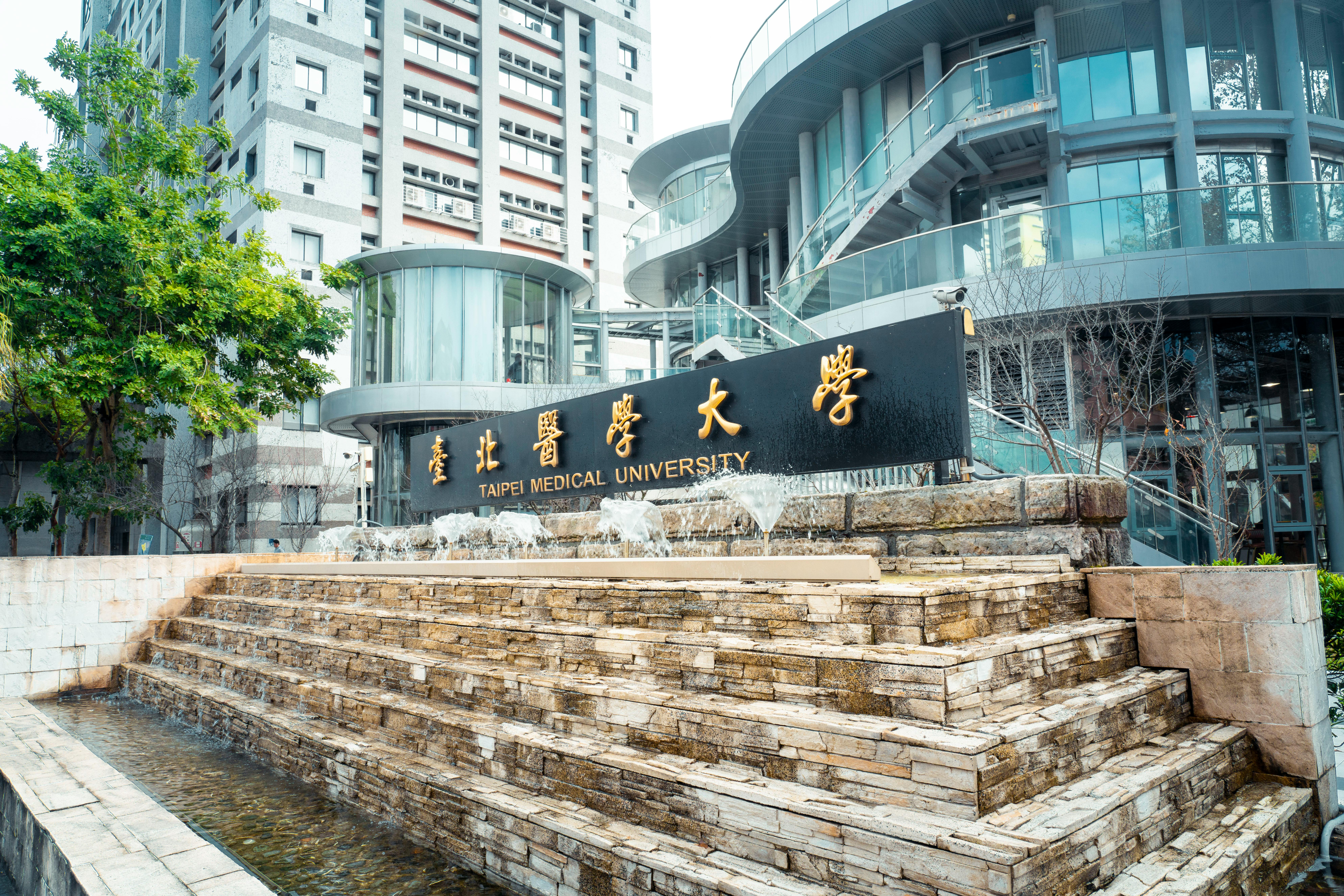 Modern architectural view of Taipei Medical University with fountain feature outdoors.