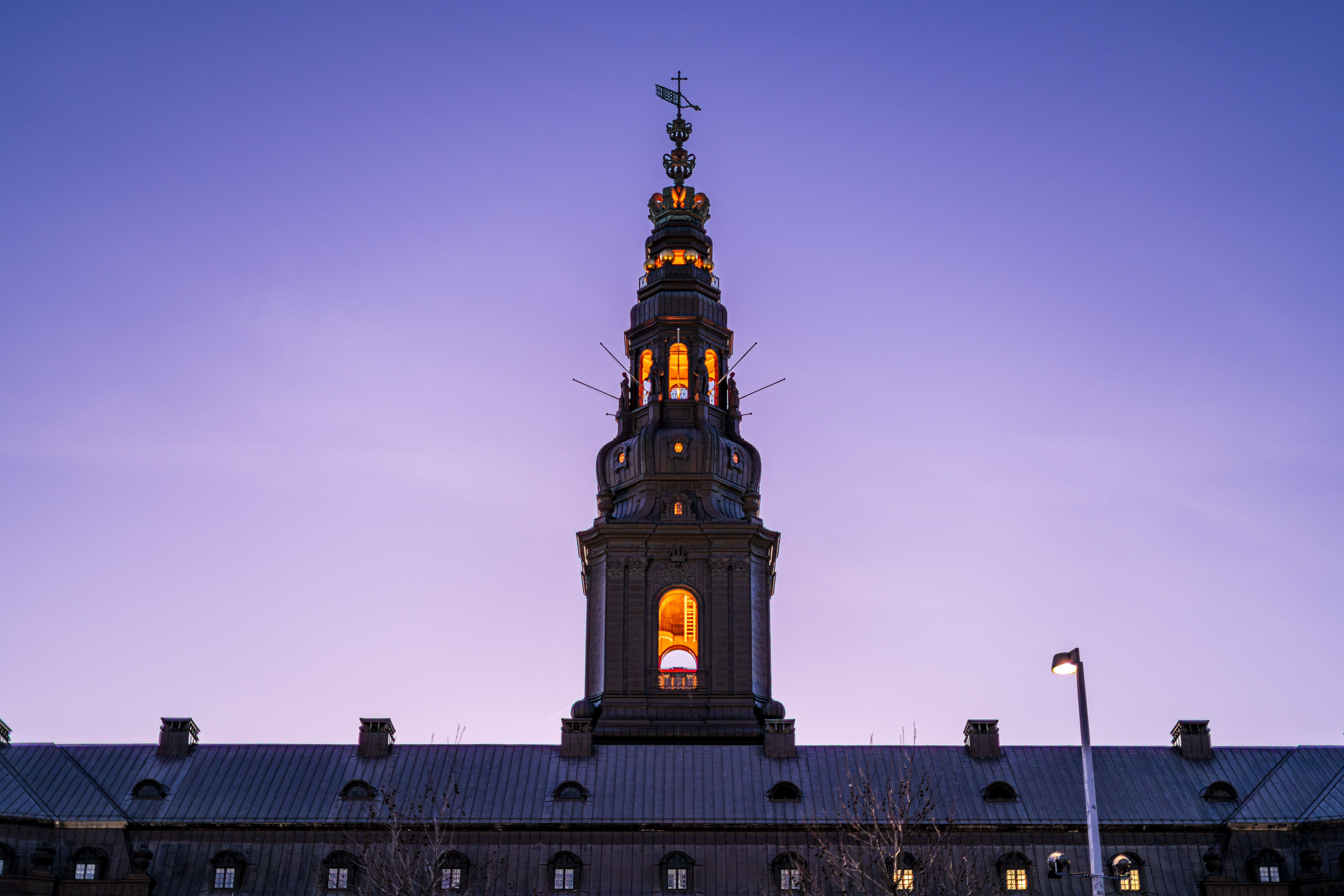 Stunning view of Christiansborg Palace illuminated against a twilight sky in Copenhagen, Denmark.
