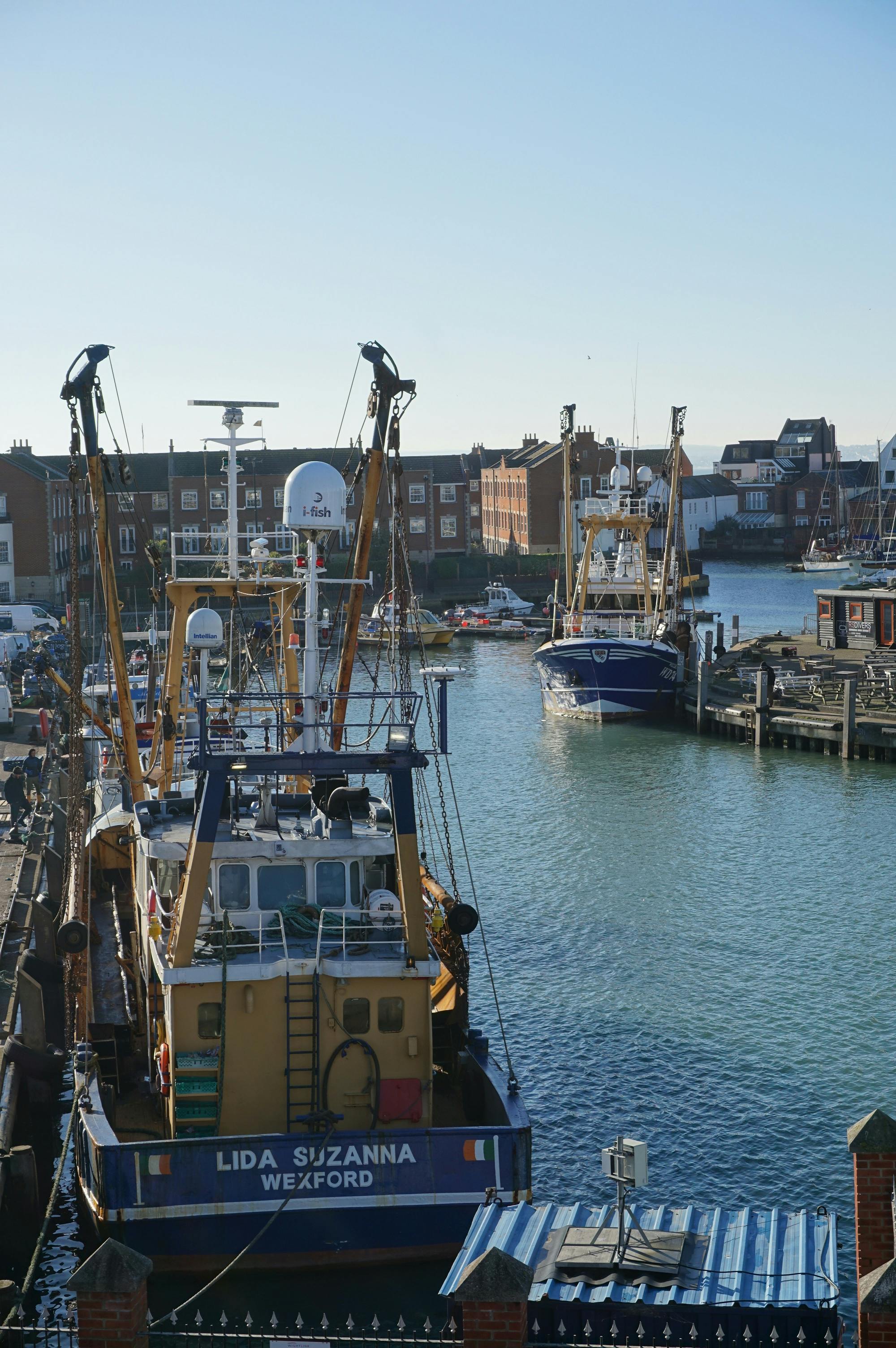 Fishing boats moored in Portsmouth harbor, capturing the vibrant marine life and cityscape.