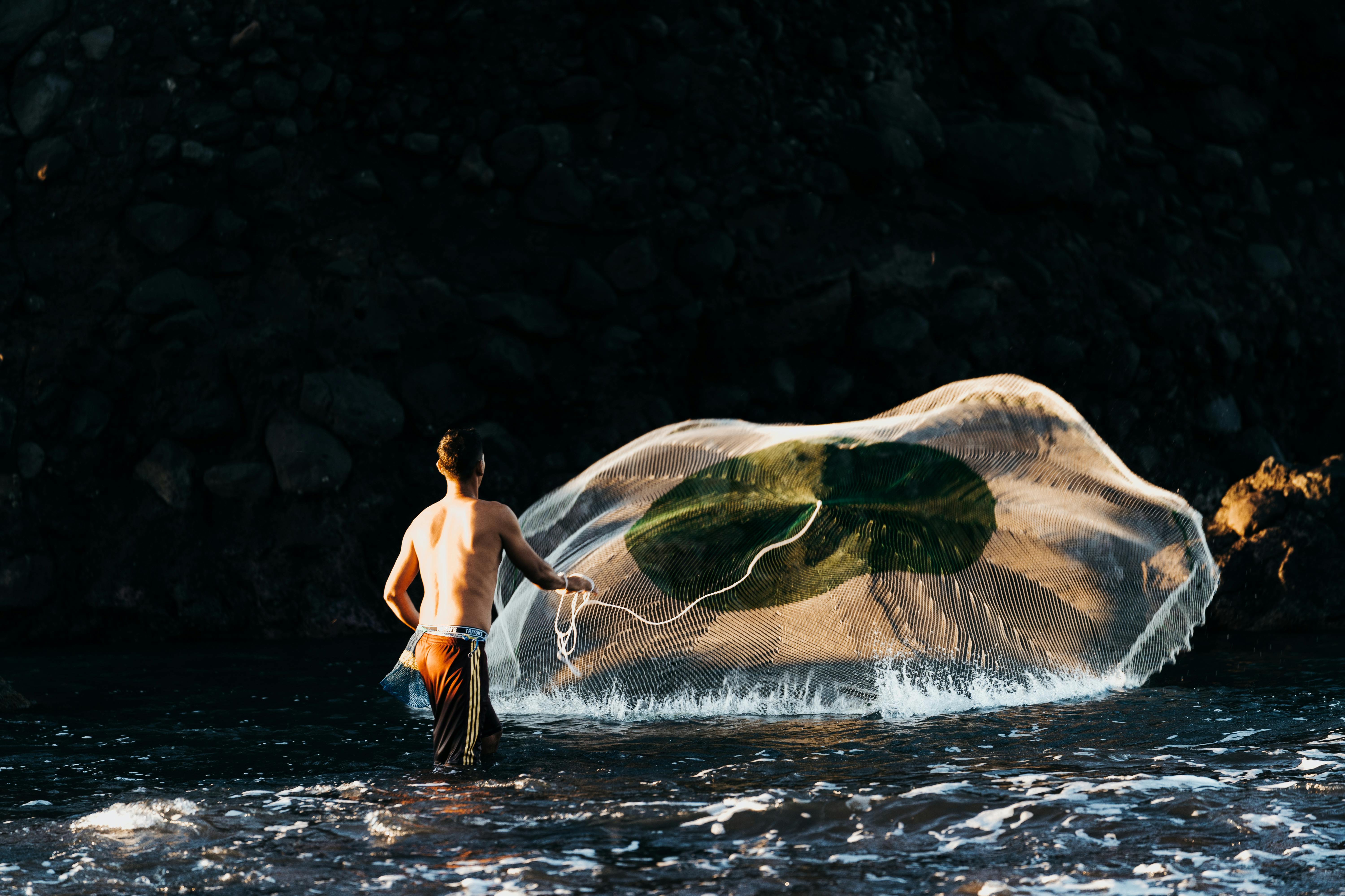 A fisherman skillfully casts his net in the early morning light at El Tunco Beach.
