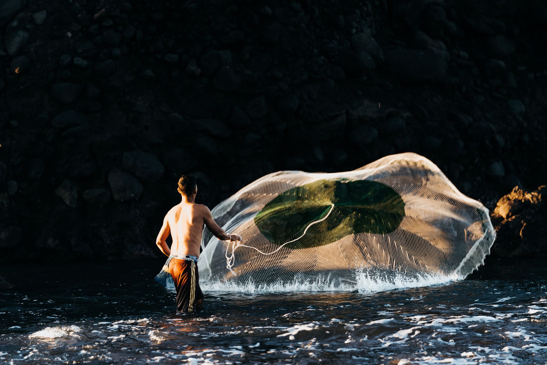 A fisherman skillfully casts his net in the early morning light at El Tunco Beach.
