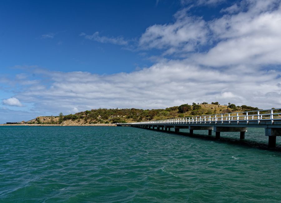 Long pier stretching into the sea with a scenic view of the coastline under a bright blue sky in Victor Harbor, Australia.