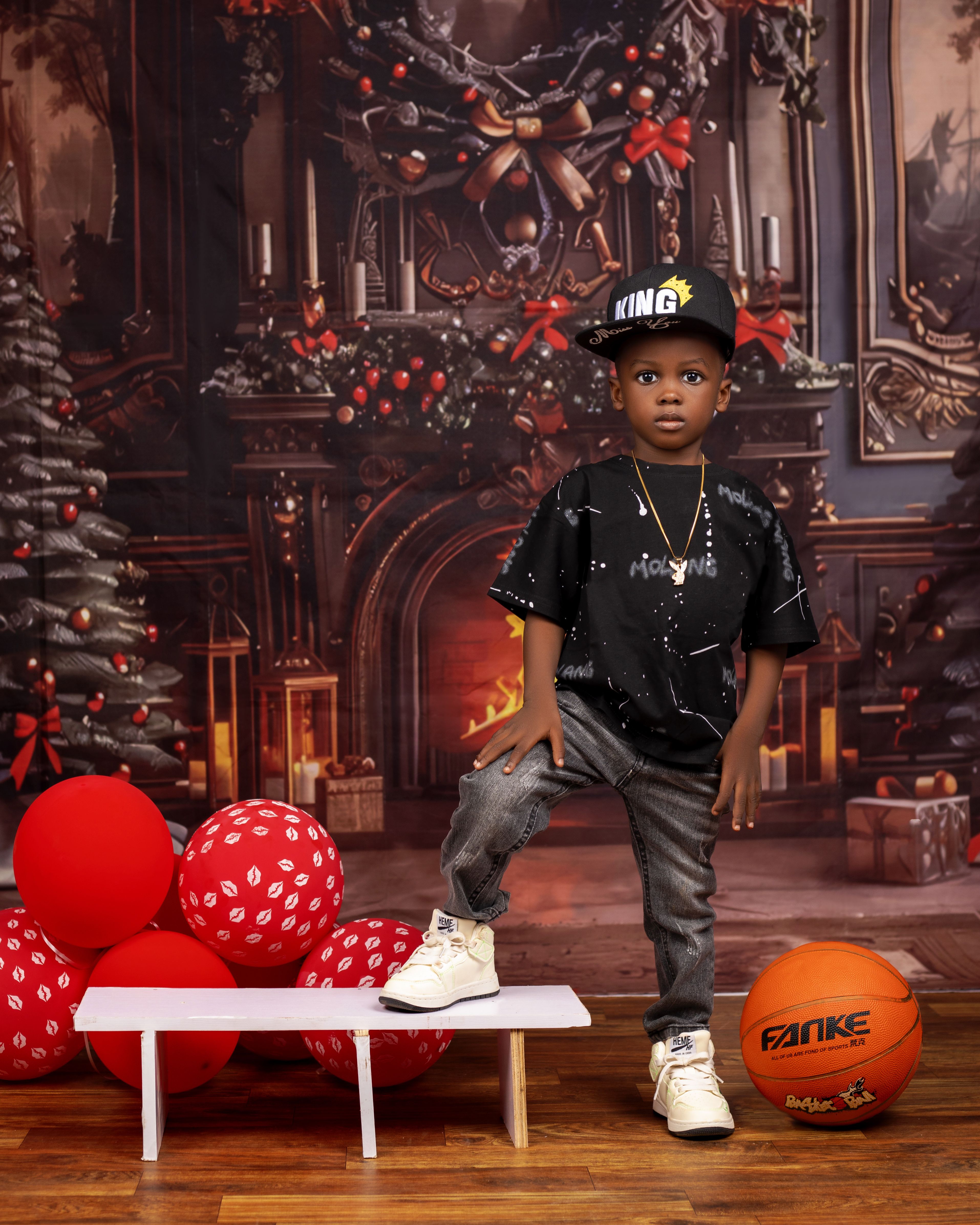 Young boy posing indoors with Christmas decorations and balloons.