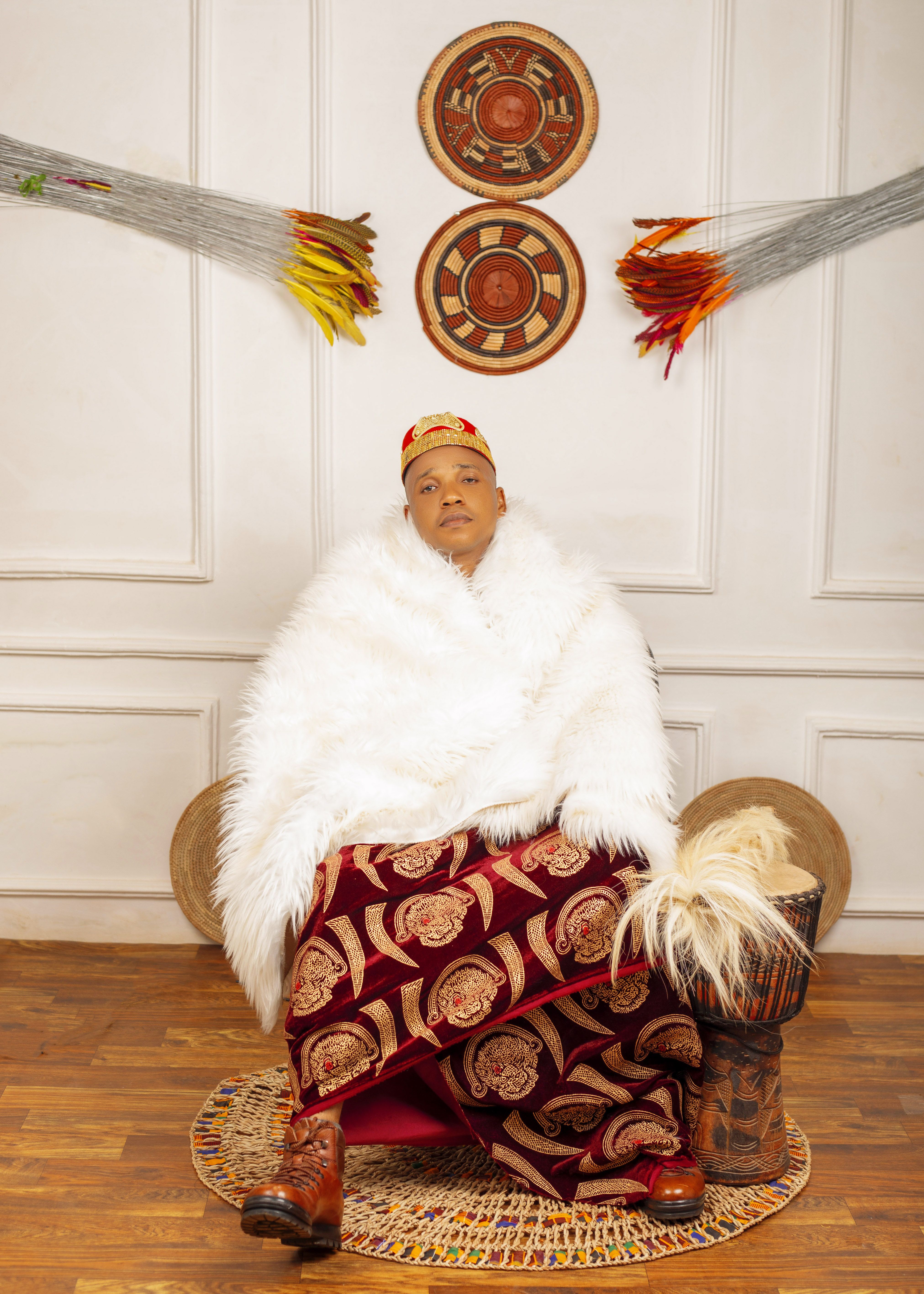 Person seated in traditional attire with cultural decor indoors, embodying heritage.