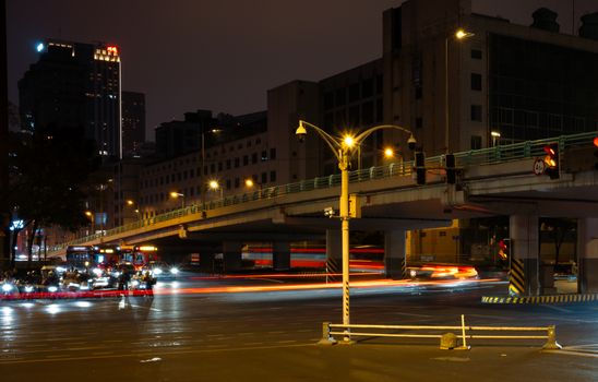 Dynamic city intersection captured at night with light trails and urban architecture.