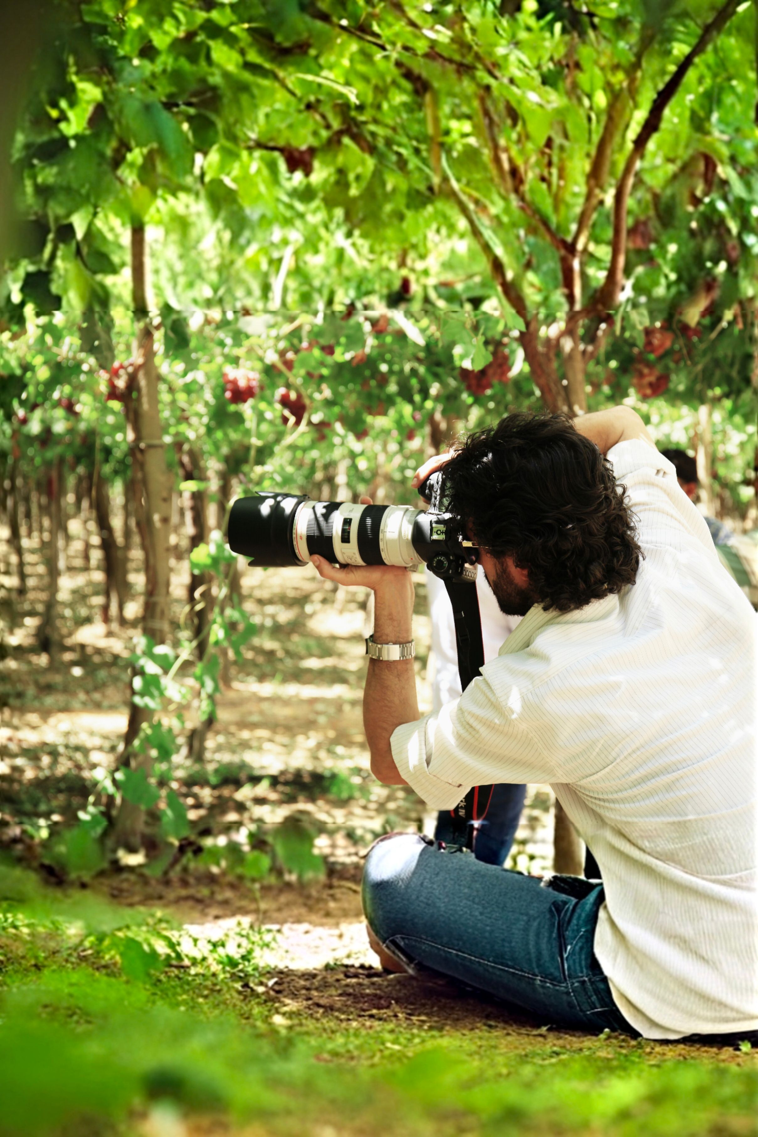 Photographer capturing nature with camera in lush vineyard setting
