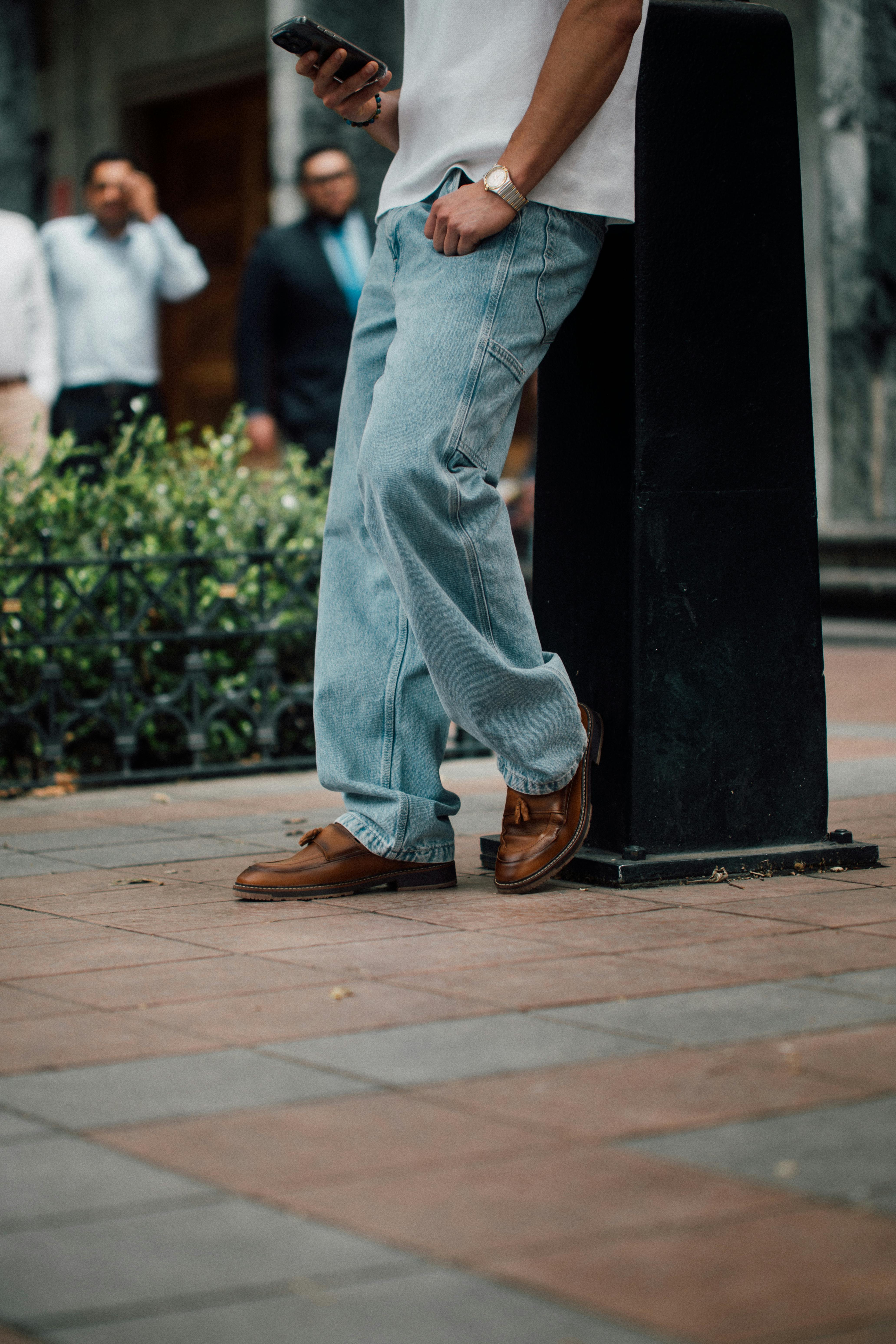 бесплатная Мужчина в джинсах и лоферах опирается на столб в Куэнке, Эквадор. Стоковое фото