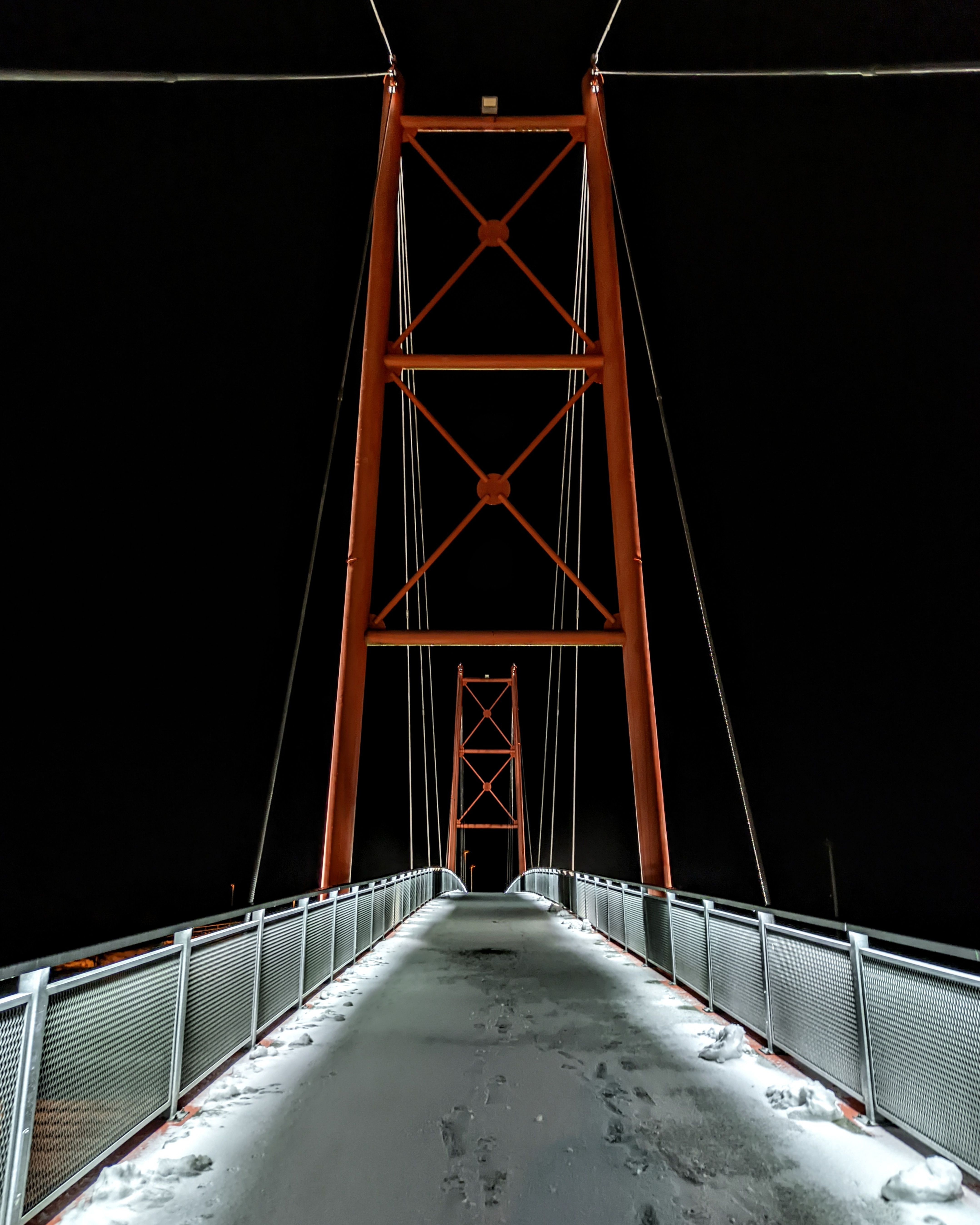Illuminated suspension bridge at night covered in snow in Vaida, Estonia.