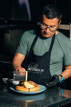 Chef skillfully plating a gourmet dish in a professional kitchen setting, showcasing culinary expertise.