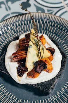 A gourmet dessert featuring cheese, nuts, and fruit on a decorative plate, perfect for culinary presentations.