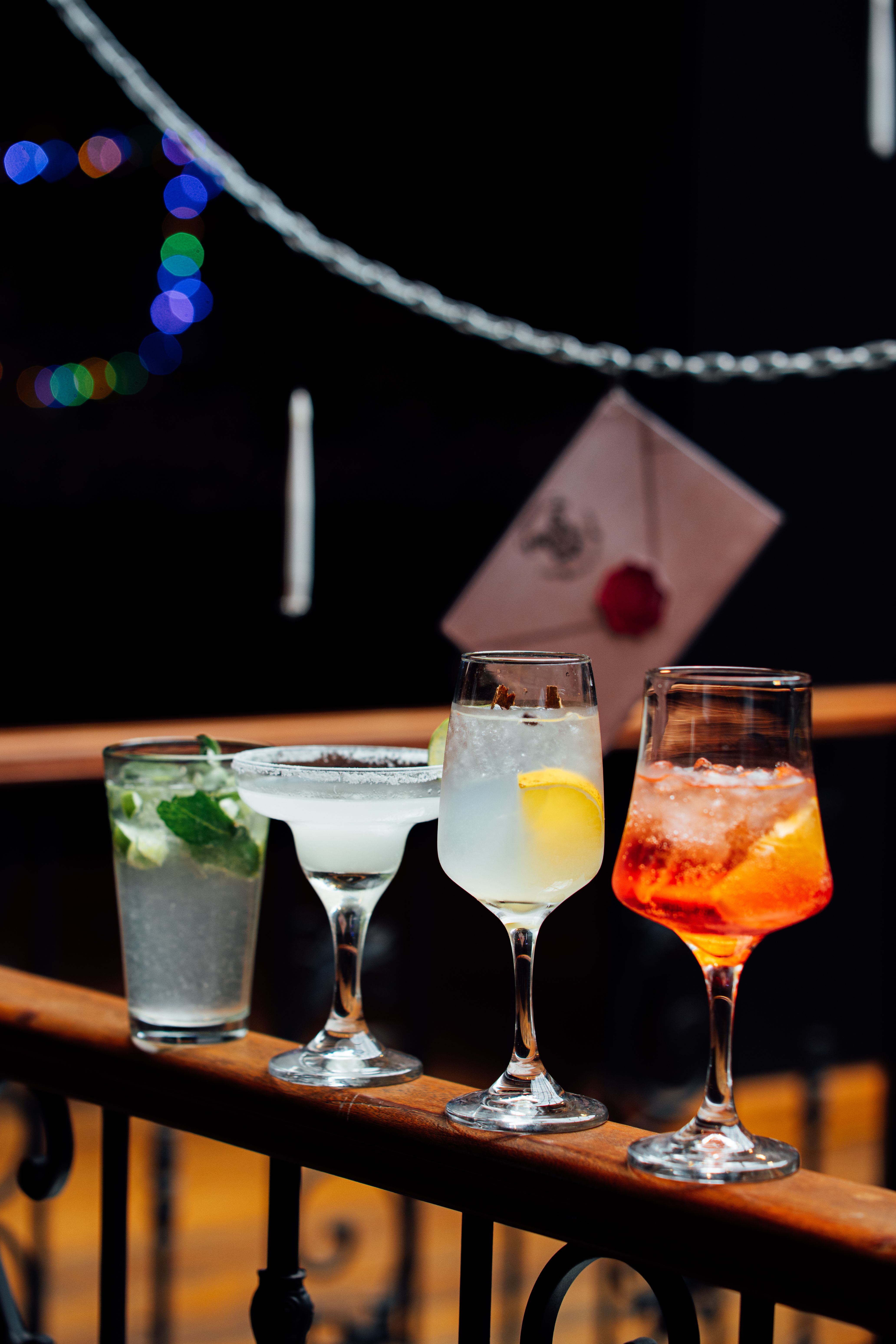 Colorful cocktails lined up on an elegant balcony railing at night