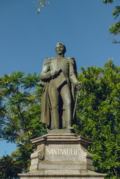 Bronze statue of Santander in sunny Buenos Aires park, lush greenery background.