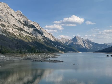 Stunning view of the Rocky Mountains over a serene lake under a clear blue sky.