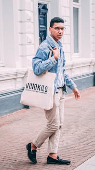Young man in urban setting carrying an eco-friendly tote bag, showcasing modern street fashion.