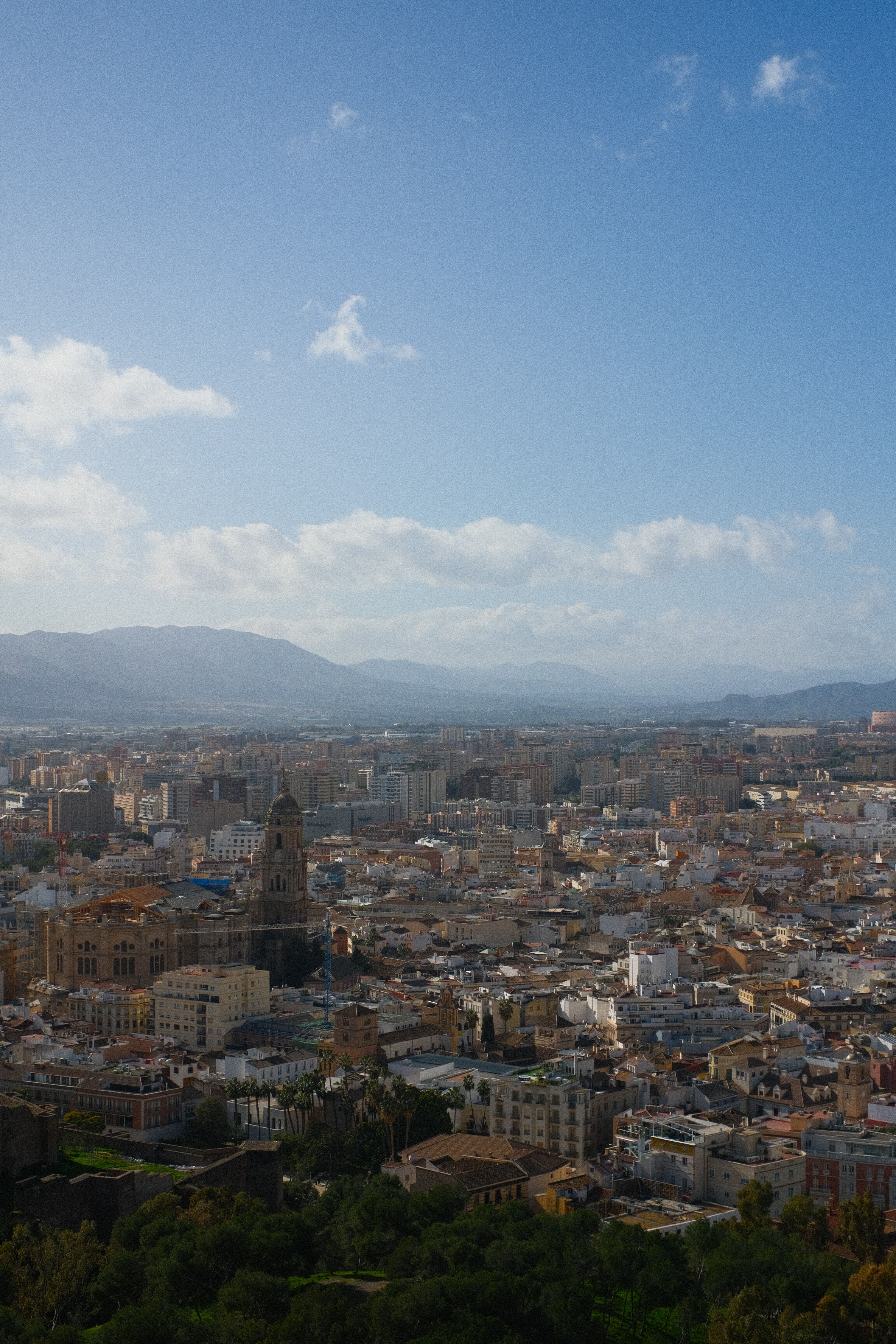 Stunning aerial view of Málaga cityscape featuring the Cathedral and distant mountains under a clear blue sky.