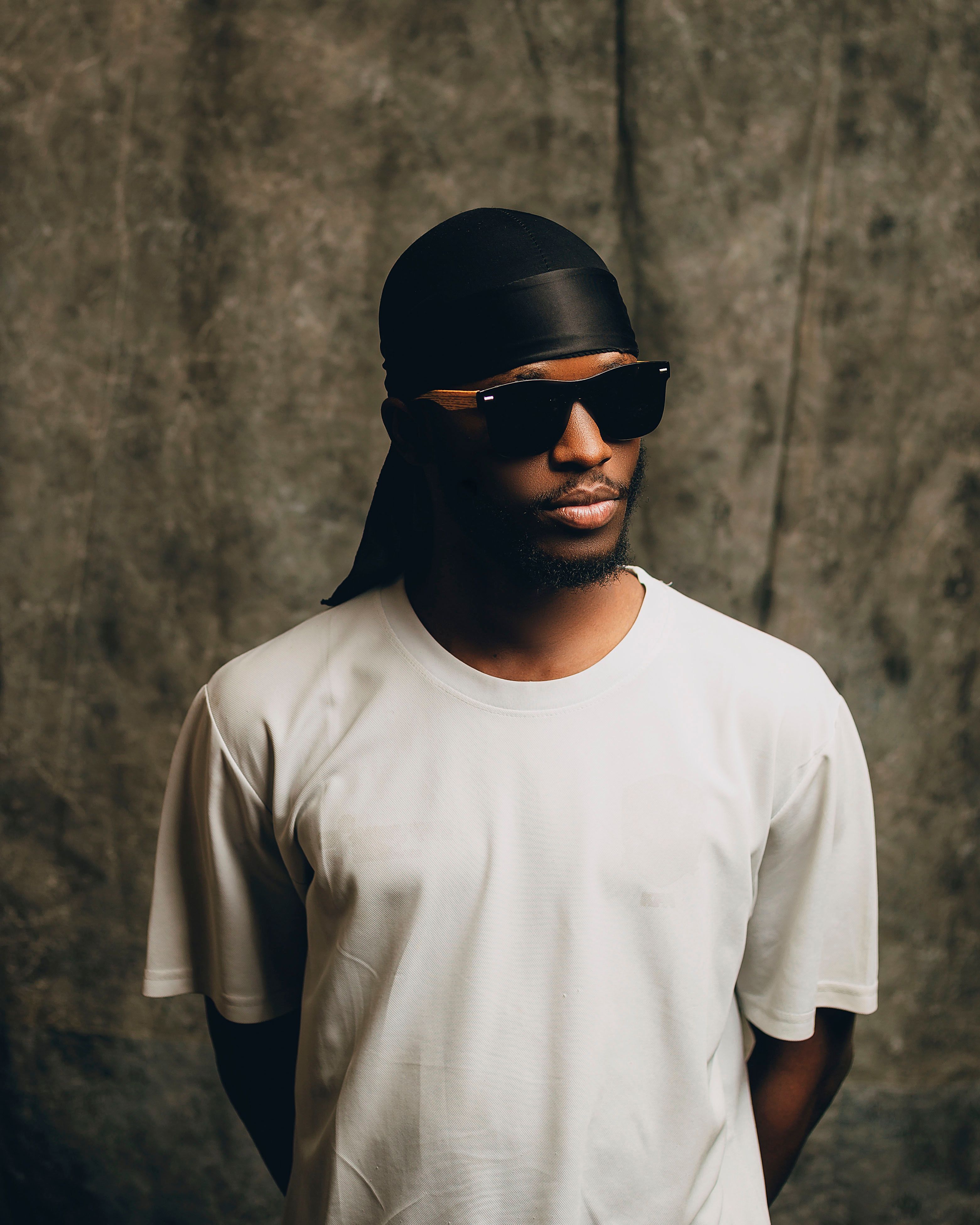 Stylish man in white shirt with sunglasses and bandana indoors.