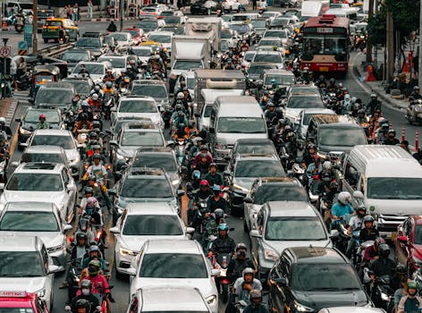 Photo by Optical Chemist Aerial view of heavy traffic congestion, capturing cars, motorcycles, and people on a bustling city street during the day.