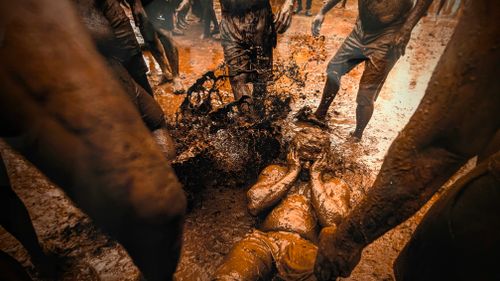 Free Participants enjoy a lively mud festival outdoors, capturing fun and spontaneity. Stock Photo