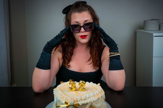 Elegant woman celebrates birthday with stylish cake and black attire.