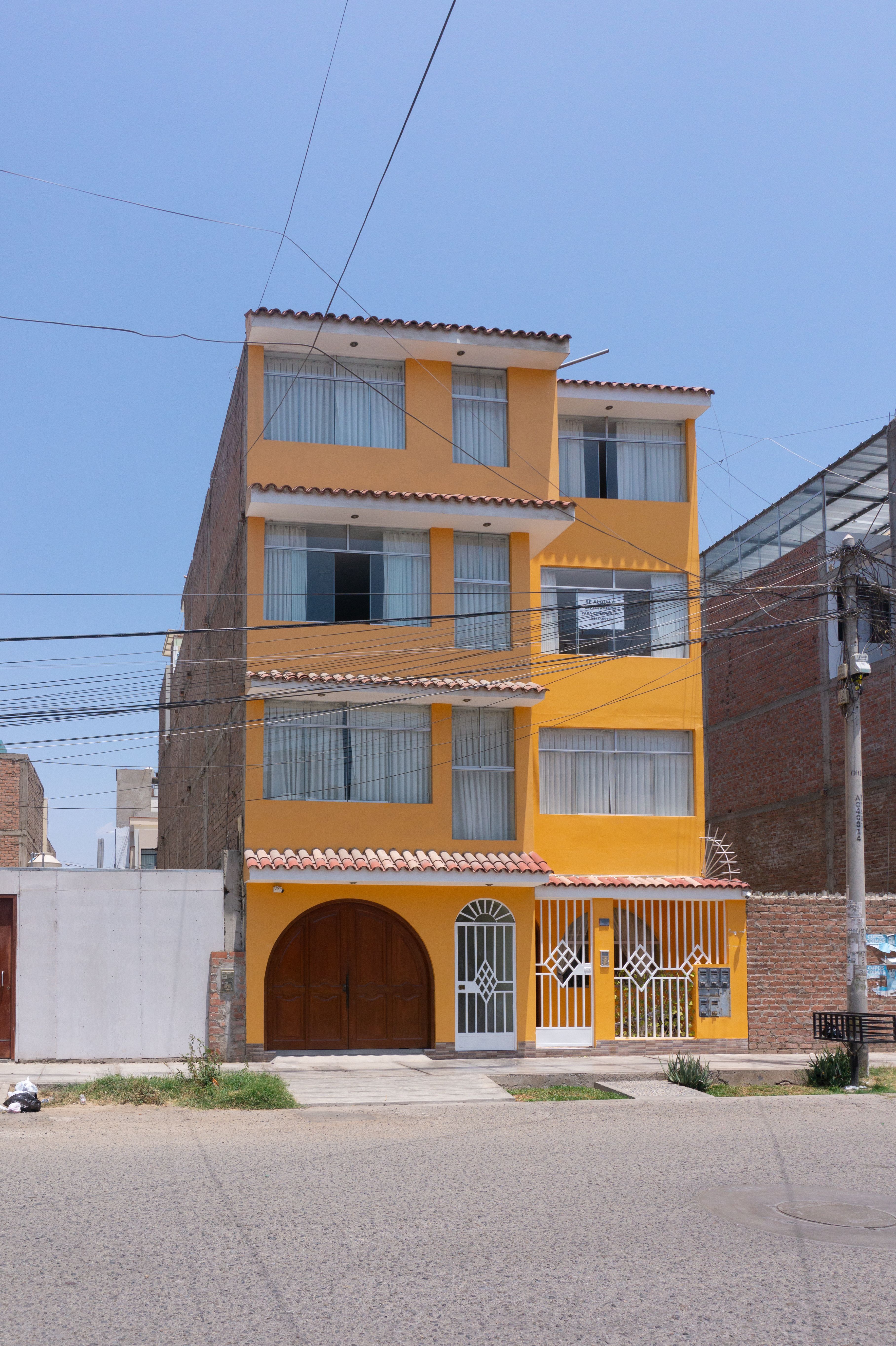 Vibrant orange multifamily building in Trujillo under clear blue sky.