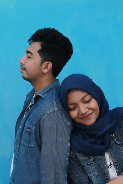 Man in Blue Denim Jacket Beside Woman in Blue Hijab