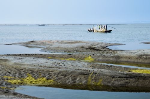 Free Traditional boat on calm water with fishing nets in serene coastal landscape. Peaceful. Stock Photo