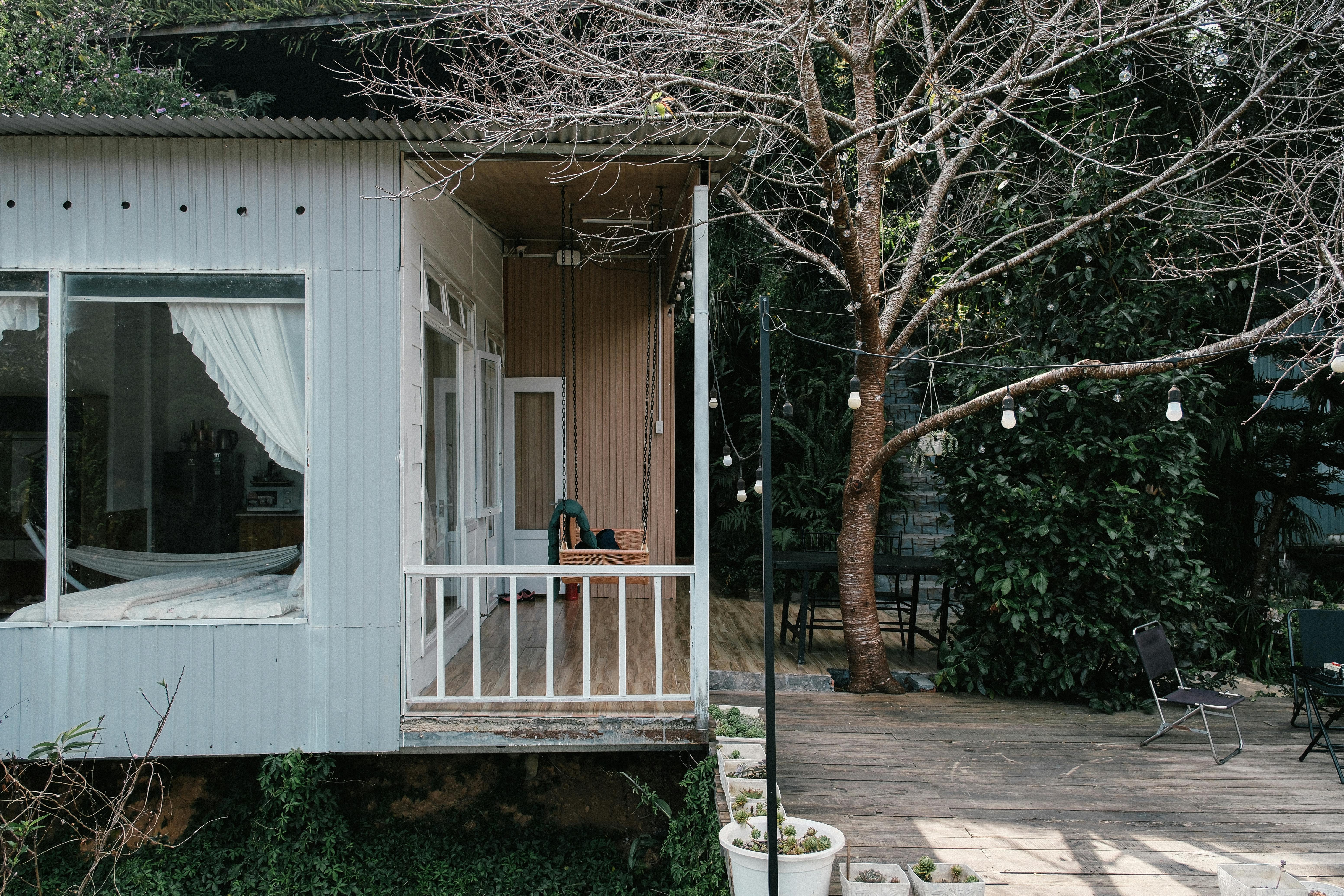 Charmant chalet avec terrasse, entouré par la nature et un arbre dénudé dans un décor hivernal.