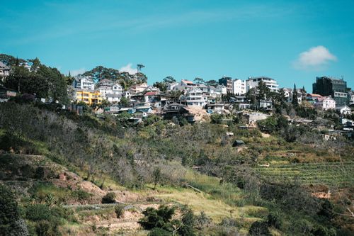 Free Picturesque view of a hillside village with colorful buildings and lush greenery under a clear sky. Stock Photo