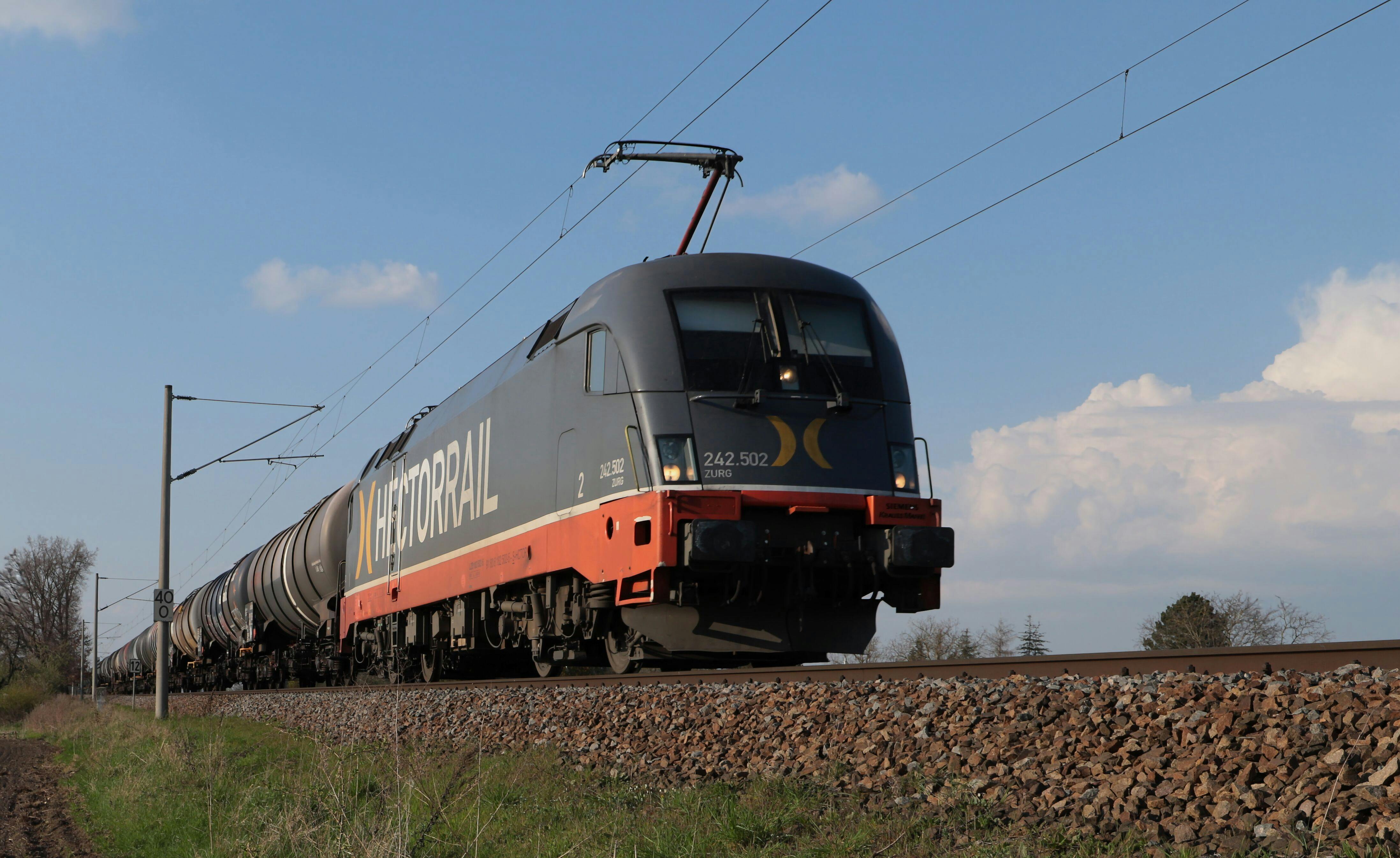 Dynamic shot of a Hector Rail cargo train moving on tracks under a clear sky.