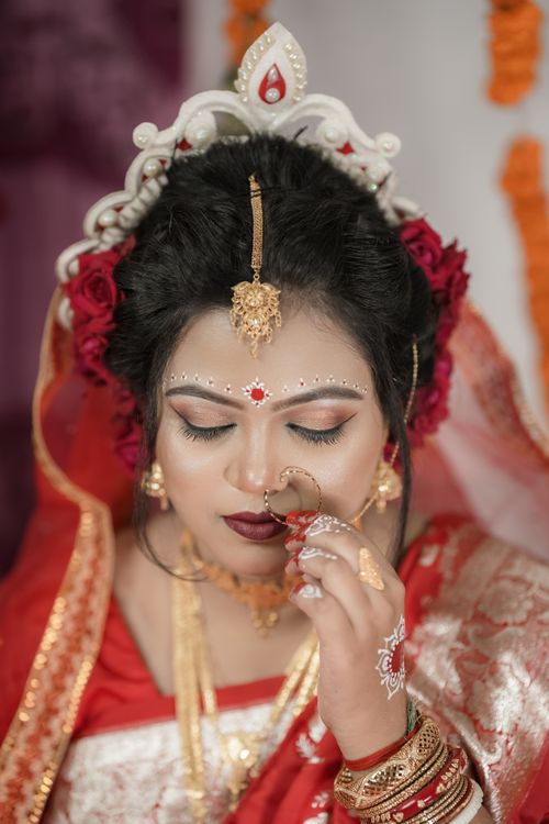 Free Beautiful portrait of a Bengali bride in traditional attire with intricate gold jewelry and bridal makeup. Stock Photo
